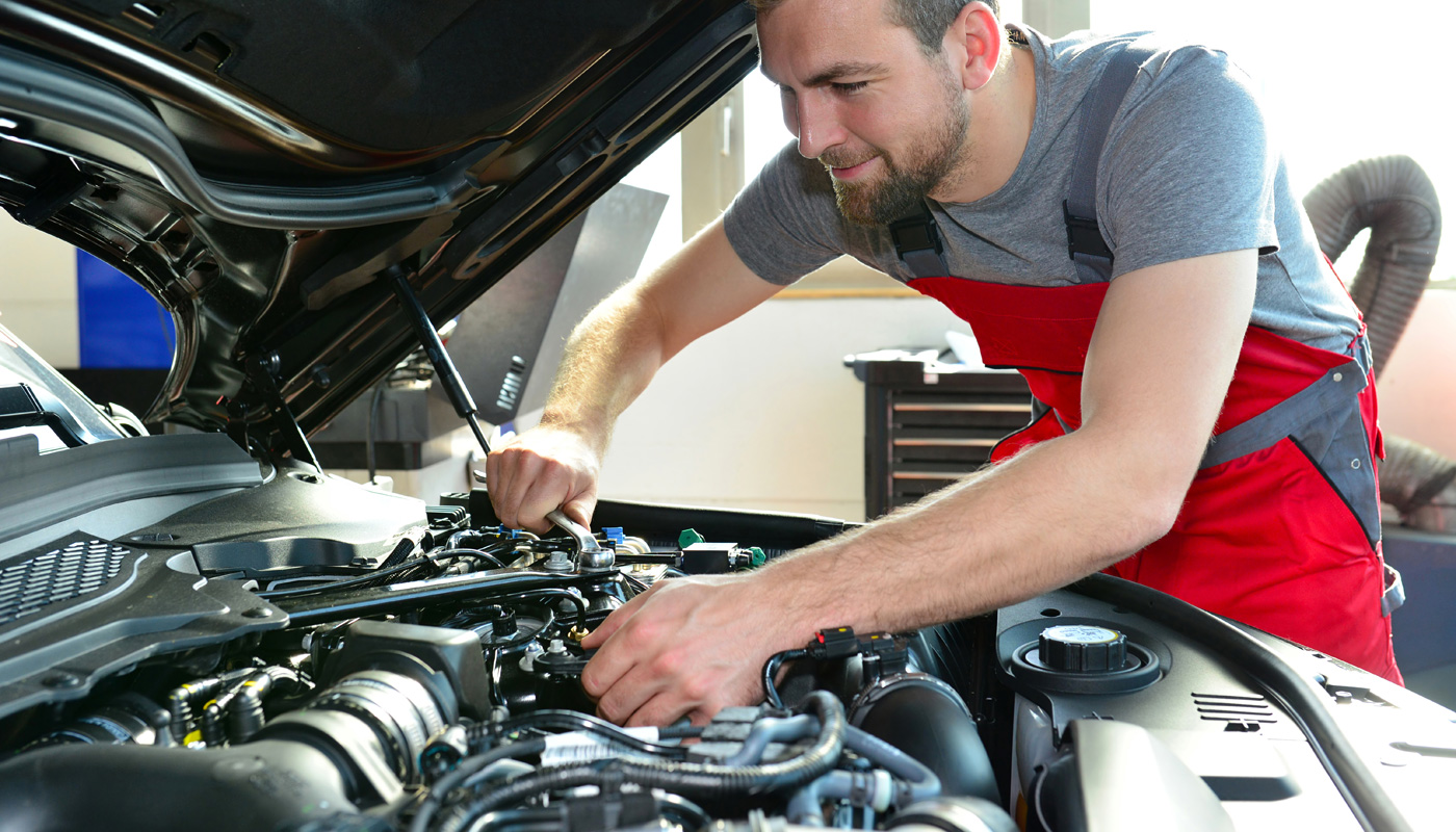 Ung mann som mekker under panseret på en bil